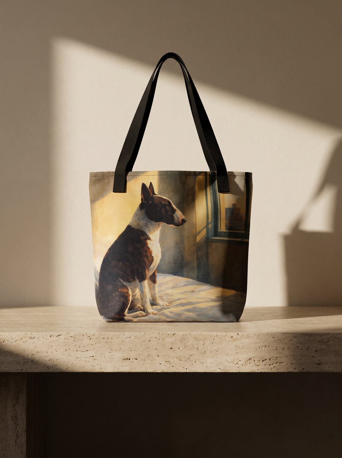The Square Tote printed with a bull terrier portrait, standing on a travertine bench in raking window light